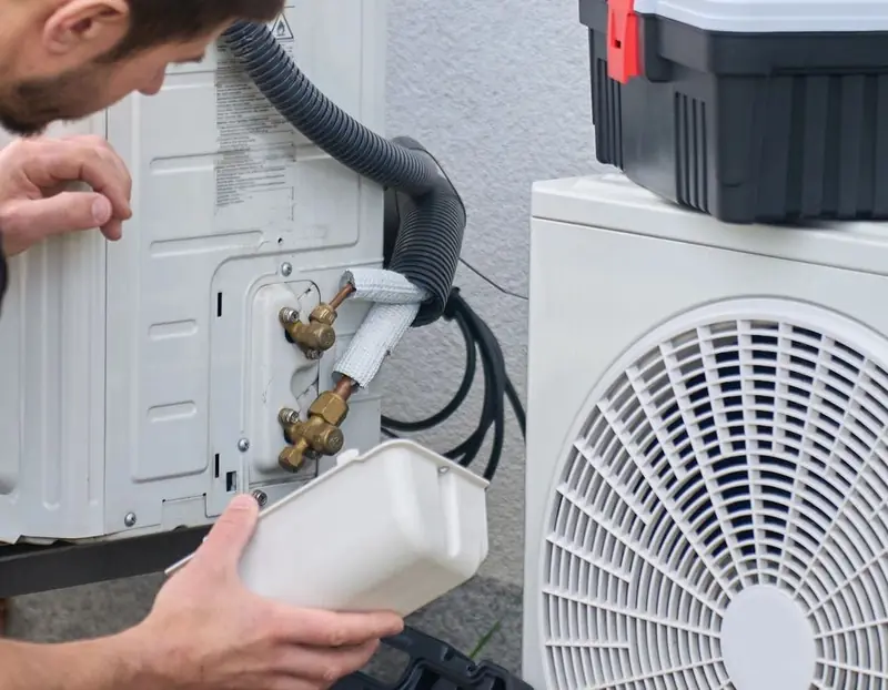 Technician connecting refrigerant lines to an outdoor heat pump unit