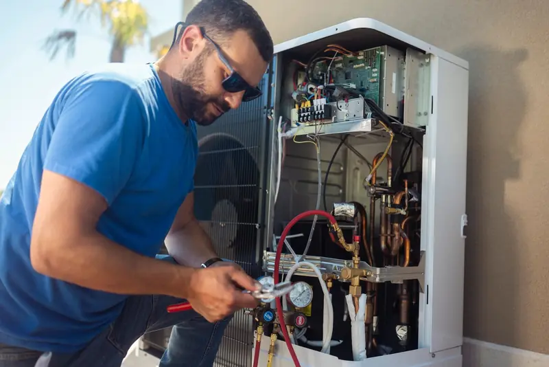 Technician checking refrigerant pressures on an HVAC unit with gauges